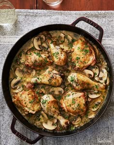 chicken with mushrooms and parsley in a skillet next to a glass of water