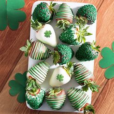 green and white strawberries are arranged on a platter with shamrocks for st patrick's day