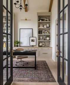 a home office with built - in shelving units and an area rug on the floor