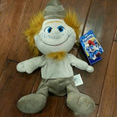 a stuffed animal with yellow hair and blue eyes sitting on the floor next to a toy