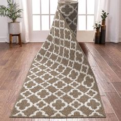 a brown and white rug on the floor in front of a window with potted plants