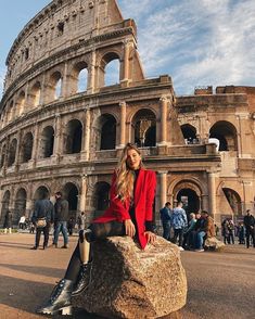 a woman sitting on top of a rock in front of an old roman collise