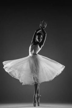 a woman in a white tutu is dancing with her arms up and legs spread out