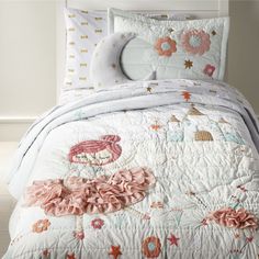 a white bed with pink flowers on the comforter and matching pillow cases in a bedroom