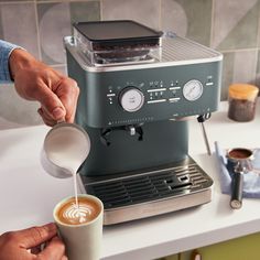 a person pouring coffee into a cup on top of a kitchen counter next to a toaster