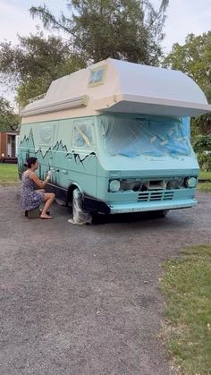 a woman kneeling down next to a parked camper