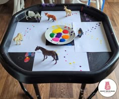 a child's play table with toys on it and paper cut out to look like horses