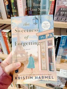 a person holding up a book in front of bookshelves