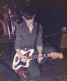 a man sitting on the ground playing an electric guitar