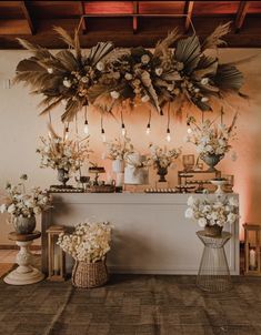 an arrangement of flowers and candles on a table in front of a wall with lights