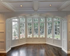 an empty room with wood flooring and large windows in the wall, along with hard wood floors