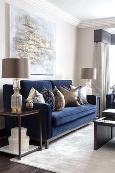 a living room with blue couches and two lamps on the table in front of it