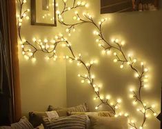 a living room with lights on the wall and a tree branch in the middle of it