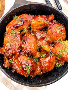 a skillet filled with chicken covered in sauce and garnished with parsley