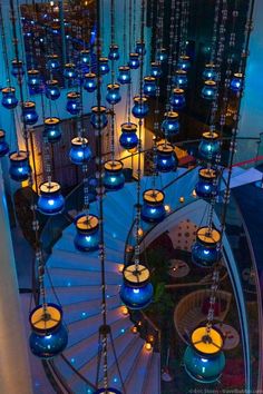 a spiral staircase with blue glass balls hanging from it's sides and lights on the ceiling