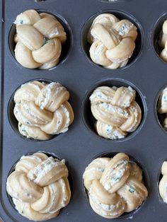 twelve cupcakes in a muffin tin with white frosting braided around them