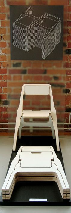 two white chairs sitting next to each other in front of a brick wall with a painting on it