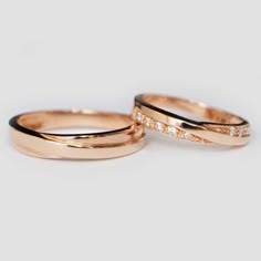 two gold wedding rings with diamonds on top and bottom, set against a white background