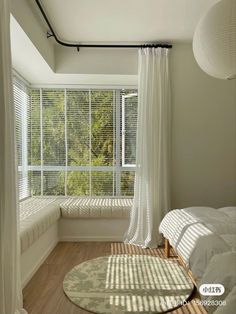 the sun shines through the window in this bedroom with white drapes on the windowsill