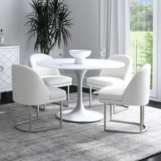 a white table with four chairs and a potted plant next to it on a rug