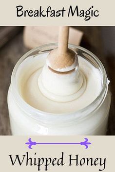 a jar filled with whipped honey sitting on top of a table next to a wooden spoon