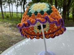 an orange and purple crocheted hat sitting on top of a white plastic table