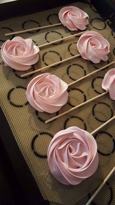 some pink icing on top of sticks in the shape of rosettes and circles