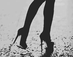 black and white photograph of woman's legs in high heeled shoes on wet ground