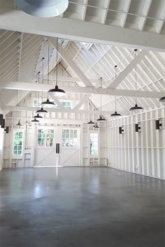 an empty room with several lights hanging from it's ceiling and windows above the floor