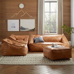 a living room with leather furniture and wood paneled walls, along with a clock on the wall