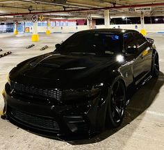 a black sports car parked in an empty parking garage with lights on it's hood