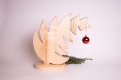 a wooden sculpture with a red ornament hanging from it's side on a white background