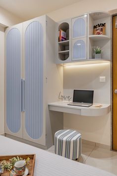 a laptop computer sitting on top of a desk next to a white bed in a bedroom