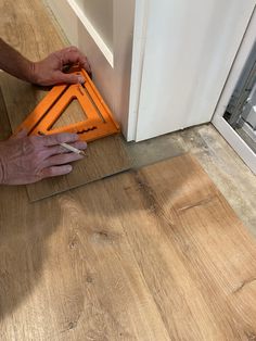 a man is working on the floor with a pair of scissors and an orange triangle