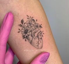 a woman's arm with flowers and a heart tattoo on the left side of her body