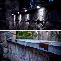 there are several lights that are on the side of this stone wall, and one is lit up at night