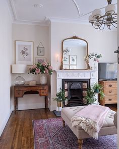 a living room filled with furniture and a fire place under a mirror on top of a wooden floor