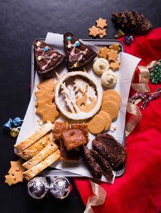 an assortment of cookies and pastries are arranged on a tray next to silverware