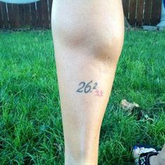 a person standing in the grass with their foot up and number 26 tattooed on his leg