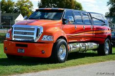 an orange and black truck parked on the side of a road next to another vehicle