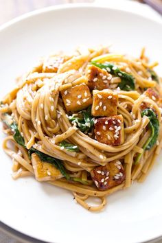 a white plate topped with noodles and tofu