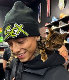 a man with a cat on his shoulders in a store looking at the cell phone