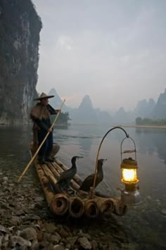 a man on a raft with ducks in the water and a lantern hanging from it's side