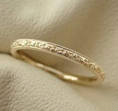 a close up view of a wedding ring on a white cloth with the background textured