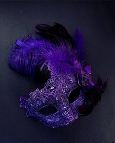 The brocade lace design with feathers add a touch of sophistication and the jewels are carefully placed to catch the light and enhance your beauty. Securely and comfortably fits every face shape so you can enjoy a perfect evening at the masquerade ball.  Age Group/Gender - Adult/Women  Size/Type - One size fits all adults  Mask Color - Purple  Mask Material - Polyresin/Fabric  Accent Material - Gems Ball Room Mask, Black And Purple Masquerade Mask, Masquerade Outfit Ideas Purple, Purple Masquerade Quinceanera Ideas, Dark Purple Quinceanera, Masquerade Mask Feathers, Masquerade Mask Ideas, Masquerade Homecoming, Masquerade Quinceanera Ideas