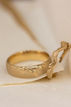 two gold wedding bands with leaves on them