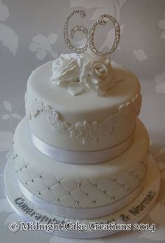 a three tiered cake with white frosting and flowers on top is decorated with the number 60