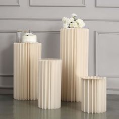 three white vases with flowers in them sitting on the floor next to each other