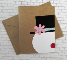 two brown envelopes with pink flowers and a black top hat on them, sitting against a white brick wall