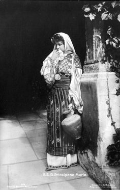 an old black and white photo of a woman in traditional dress holding a potted plant